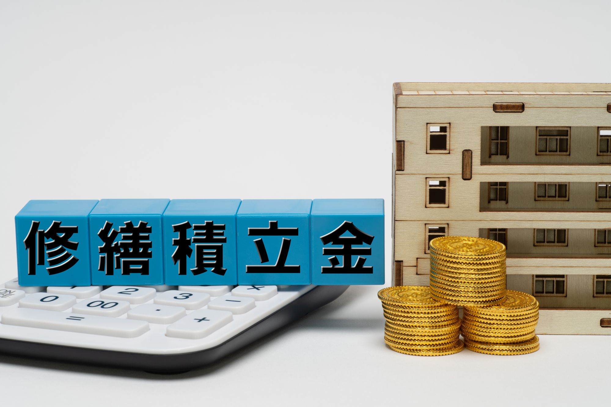 修繕積立金のブロックとマンションの模型・電卓・硬貨